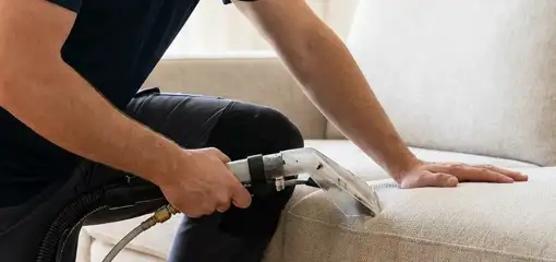 Professional upholstery cleaner deep-cleaning a fabric sofa with a handheld extraction tool, Sioux Falls, SD.